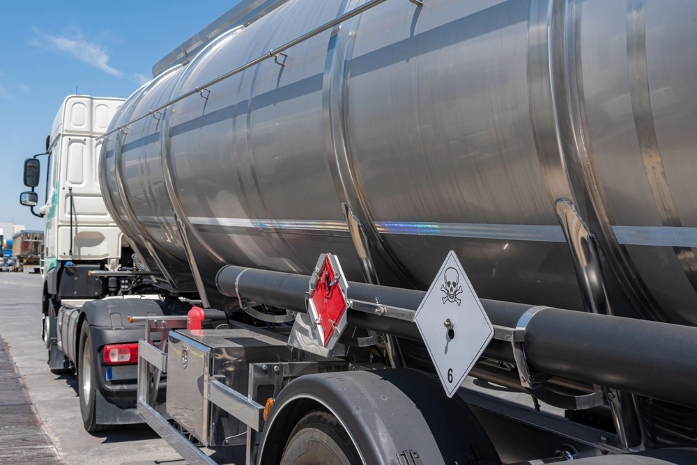 Large tanker truck displaying hazardous material warning labels for flammable and toxic liquids.