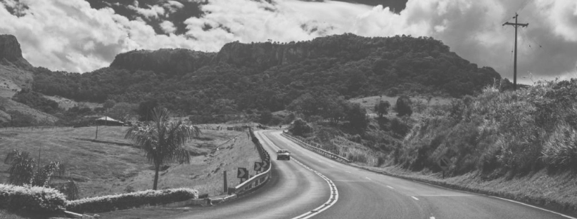 Black and white photo of a car on a winding road in a hilly area, used for an article on fender benders.