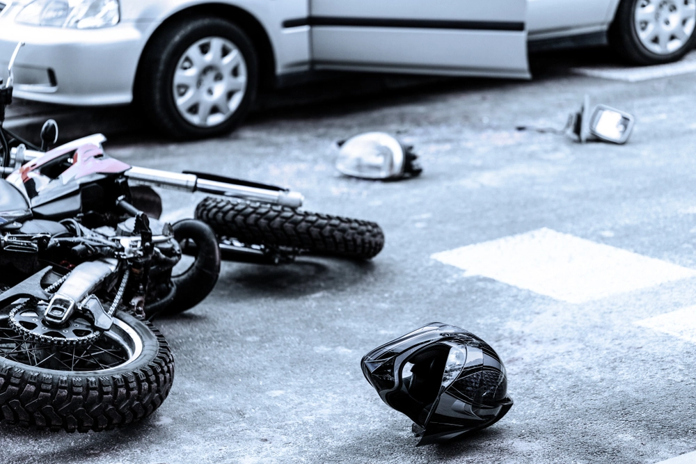 Helmet and motorcycle on the street after car crash.