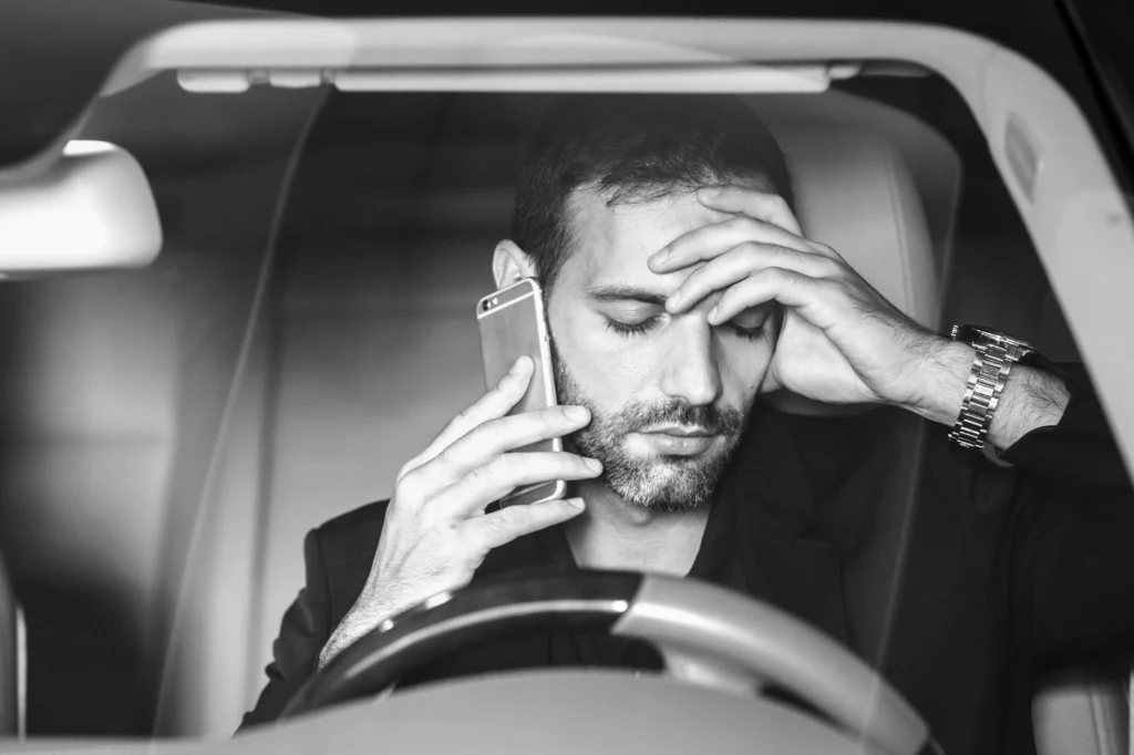 Stressed man on phone in car after accident.